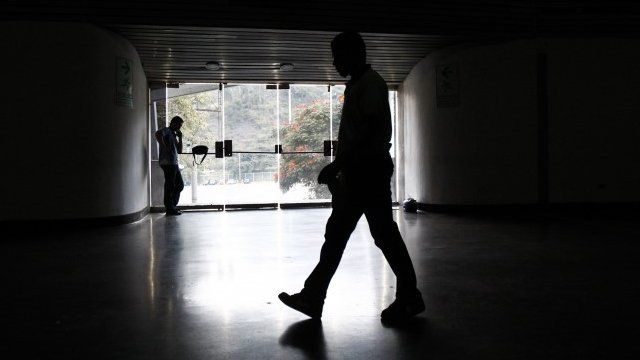 A security guard walks past an exit door as he waits for the power to return after a blackout during the FIBA Americas Championship basketball game between Paraguay and Dominican Republic in Caracas