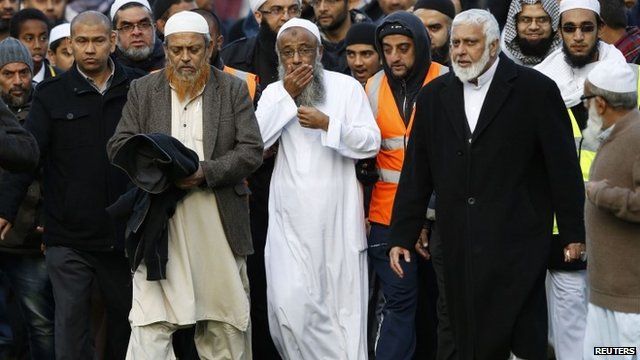 Sattar Taufiq walks with members of the community after funeral prayers for his wife and children at Spinney Hill Park in Leicester