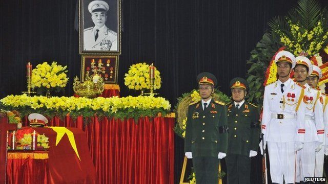 Soldiers stand to attention next to coffin
