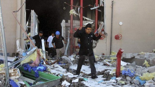 People climbing over debris at the factory