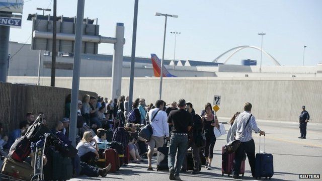 Evacuated passengers wait on a road after a shooting at the airport