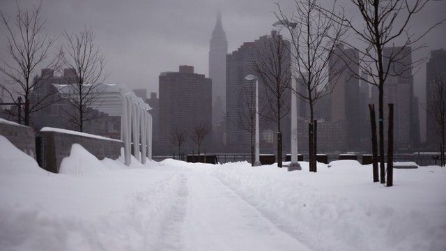 The Empire State Building and the skyline is seen from a path of snow in the Queens borough of New York