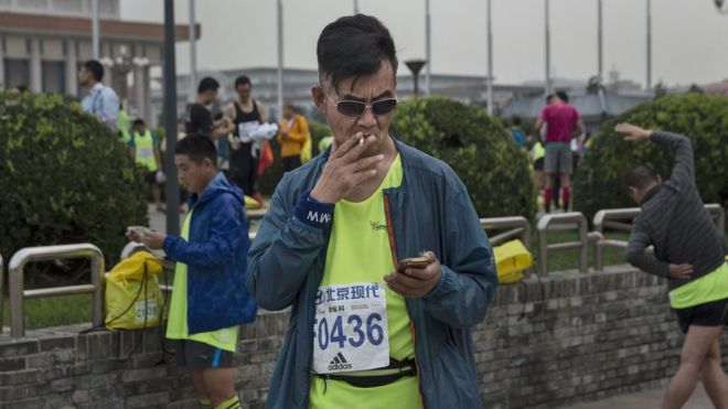 A participant smokes a cigarette before competing in the 2015 Beijing Marathon on 20 September