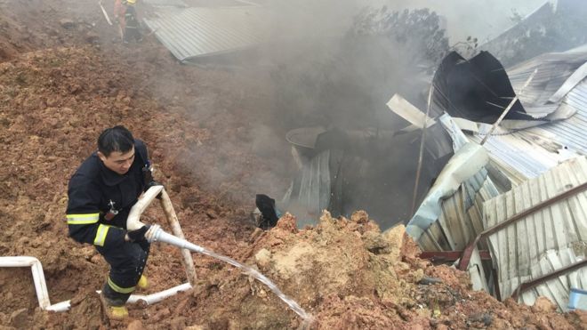 Rescuers spray liquid next to damaged sheds at the site of a landslide at an industrial park in Shenzhen, Guangdong province, China, December 20, 2015.