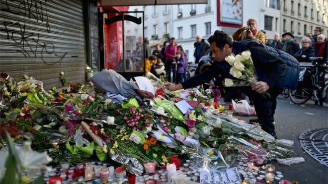A man places a flower outside of the La Belle Equipe restaurant on Rue de Charonne following Friday's terrorist attack