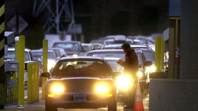 A US Customs officer (R) is on duty as cars line up to pass through the customs station at Blaine, Washington to enter Surrey, Canada 20 December 1999, as the wait to cross the border increased in the wake of the manhunt for a possible accomplice of an Algerian terrorist in custody in Canada.
