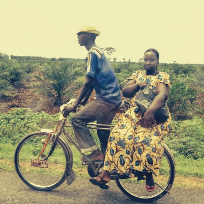 Woman balanced on the back of a bicycle in Burundi