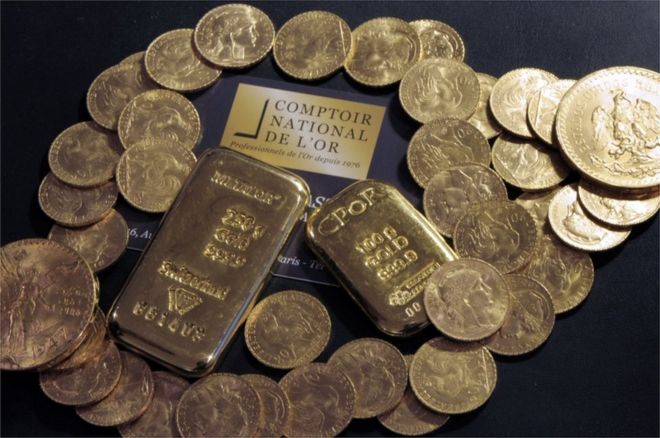 Dos barras y monedas de oro en el Comptoir National de l'Or una tienda que compra, vende y valoriza oro y joyas en París.