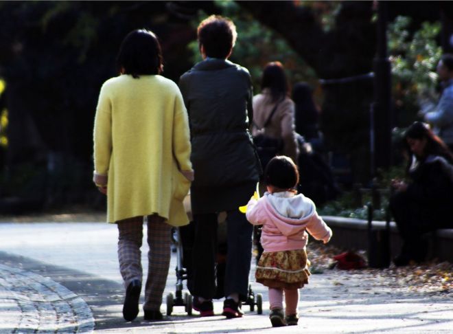 This picture taken on 12 December 2015 shows a family strolling at a park in Tokyo. Japan's top court will rule this week on a pair of 19th Century family laws that critics blast as sexist and out of touch