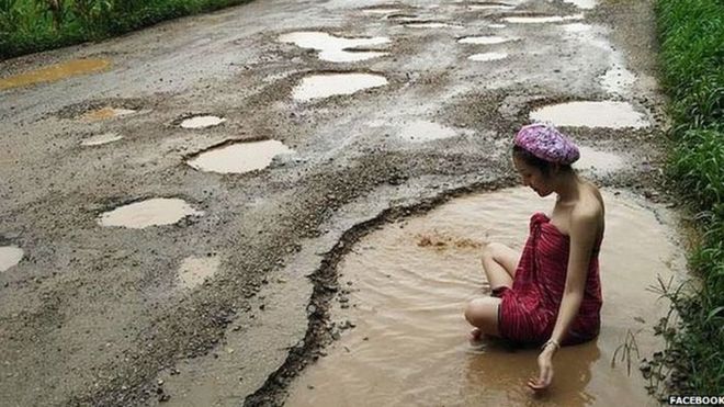 Woman bathing in pothole in Thailand