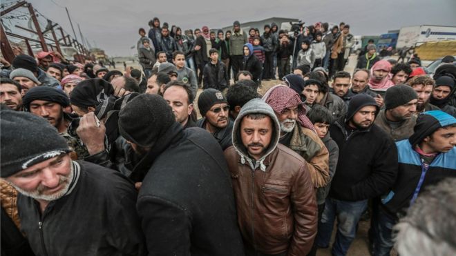 Syrians gather at the Bab al-Salam border gate with Turkey, in Syria, Saturday, Feb. 6