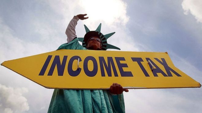 Man holding sign says 'Income tax' dressed as Statue of Liberty