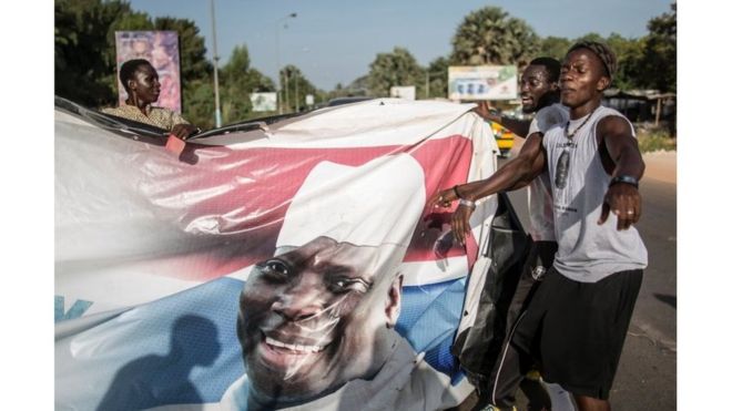 Supporters of the newly elected Gambia"s President Adama Barrow tear down posters of the incumbent Yahya Jammeh in Serekunda on 2 December 2016.