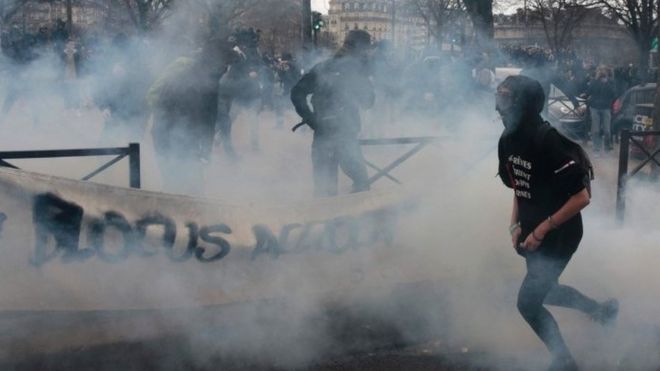People run away from a smoke grenade launched by riot police forces during a demonstration against police brutality in Paris (23 February 2017)