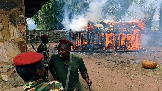 Soldiers run from a house set afire by protestors opposed to the Burundian president's bid to stand for a third term in Butagazwa, Mugongomanga, some 30km east of Bujumbura, on June 5, 2015
