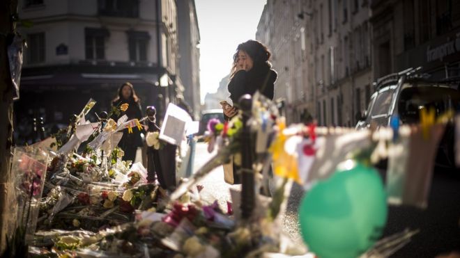 A person cries as she stands at a makeshift memorial for a tribute to the victims of a series of deadly attacks in Paris, in front of the Casa Nostra restaurant in Paris on November 13, 2015
