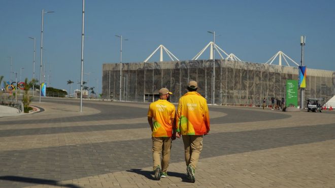 Volunteers walk towards the Olympic Aquatics Stadium in the Olympic Park