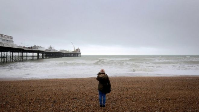 a woman watches the sea on the beach at Brighton