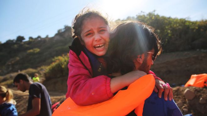 A young girl is helped moments after she arrive with other Syrian and Iraqi migrants on the island of Lesbos from Turkey on October 14, 2015 in Sikaminias , Greece