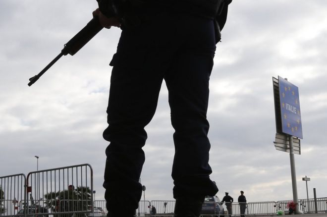 An armed French policeman stands guard at the Franco-Italian border in Menton