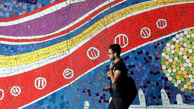 An Iranian man walks past a mural on a street in the capital Tehran