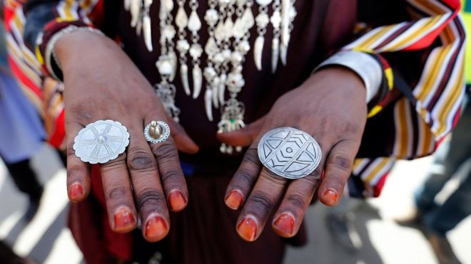 துனிஷியாவின் டேஸியுரில் நடைபெற்ற கலாசார நிகழ்வான ஒயாஸிஸ் பண்டிகையின் கடைசி நாளான வெள்ளிக்கிழமையன்று, லிபியாவின் கிராம குழுவை சேர்ந்த ஒருவர் அவருடையே மோதிரத்தை காட்டுகிறார்.