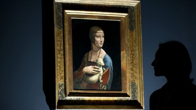 a woman posing for pictures beside a painting entitled "Portrait of Cecilia Gallerani" (The Lady with an Ermine) by Italian artist Leonardo da Vinci, London