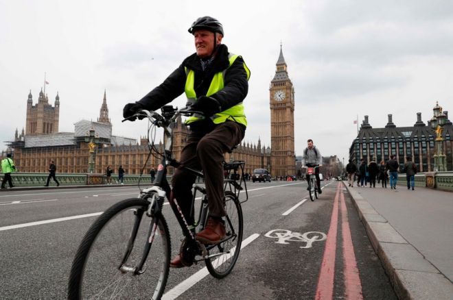Pedestrians and a cyclist cross Westminster Bridge