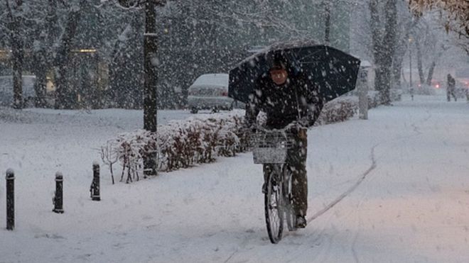 man rides his bike under heavy snow in the city centre of Ljubljana, Slovenia (13 January 2017)