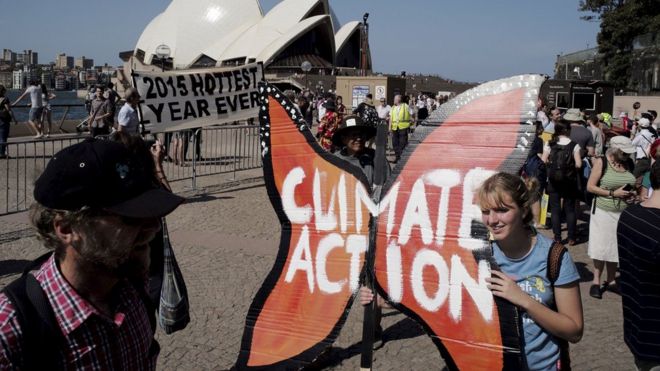 A protester holds a butterfly-shaped placard in front of the Sydney Opera House