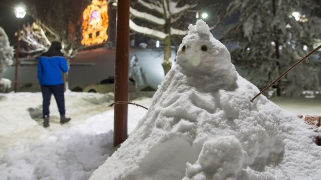 மொராக்கோவின் பகுதிகளில் குளிர் அதிகரித்து காணப்படுகையில், வெள்ளிக்கிழமையன்று இஃப்ரானே நகரத்தில் பனியில் நடந்துசெல்லும் மனிதர். .