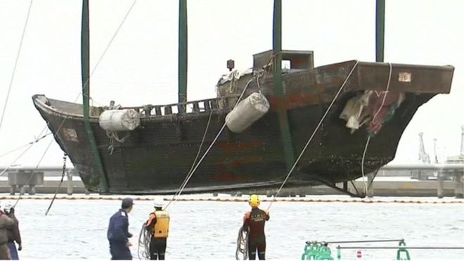 Wooden 'ghost ship' being winched onto the side of a Japanese harbour