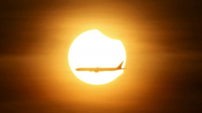 An aeroplane flies past the sun as it goes into a partial solar eclipse in Singapore March 9, 2016.