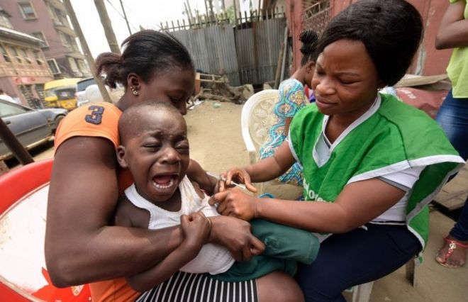 A young boy reacts as a health worker administers a measles vaccine in Lagos