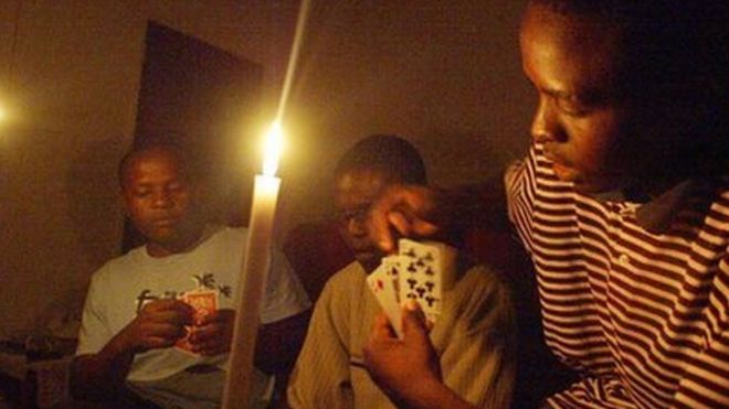 A family plays cards while candles are lit in Harare. File photo
