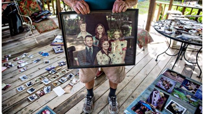 Hilton Pray, 82, holds on to one of his thousands of photographs that were damaged and now drying after an estimated 4 feet of water filled his home off of Greenwell Springs. He had an entire village he had built behind his home, starting in 1995, that featured a general store, a chapel, and countless antiques and mementos of his life as a collector, all lost. In his daughter's words, "He put mama in the highest lawnmower we had, and went back for her insulin", Denham Springs, LA