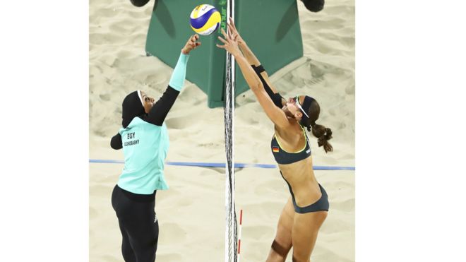 Doaa Elghobashy de Egipto cubierta de los tobillos a la cabeza, y la alemana Kira Walkenhorst en un bikini en un partido de voleibol playa