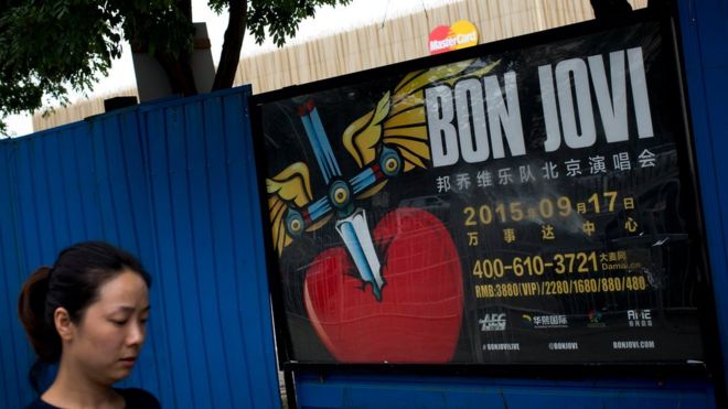A woman walks past a billboard advertising the cancelled Bon Jovi concert in Beijing, on 9 September