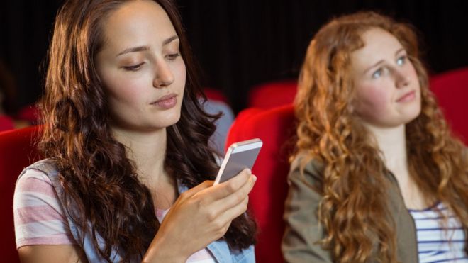 A girl texting in the cinema