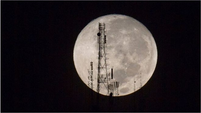 A full moon silhouettes television and radio antennas in Port-au-Prince, Haiti
