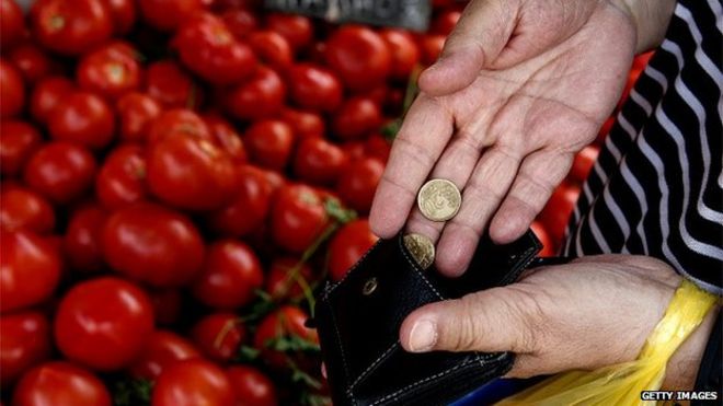 A greek person putting euros in to her wallet after buying tomatoes at a market stall