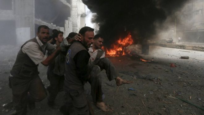Syrian Civil Defence rescue workers carry a wounded man after what activists said was a government air strike in the rebel-held Damascus suburb of Douma (16 August 2015)