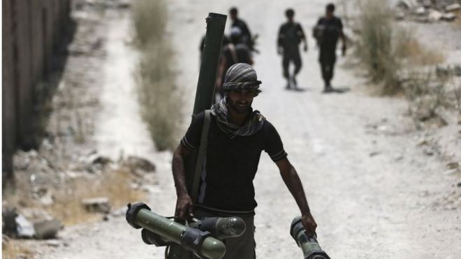 A fighter from the Free Syrian Army's Al Rahman legion carries a weapon as he walks towards his position on the front line in Jobar, a suburb of Damascus, Syria, on 27 July 2015