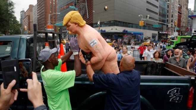 New York City Parks employee remove a statue of Donald Trump