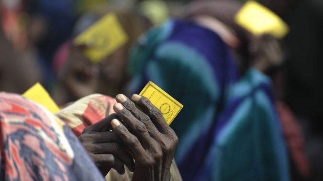 Residents of a camp for Internally Displaced Persons (IDP) hold their ratio card as they queue to receive aid in Mogadishu on August 13, 2011
