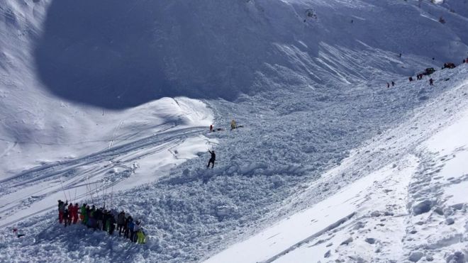 Rescue workers search through the snow brought down by the avalanche