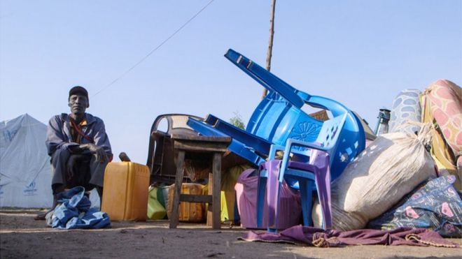 A refugee sits waiting at a reception centre in a Uganda settlement