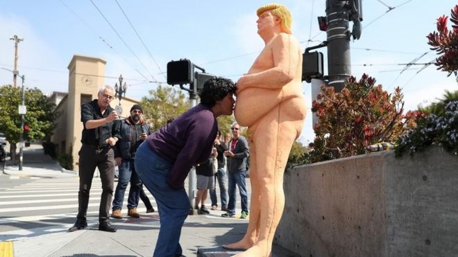 A woman kisses a statue of Donald Trump in San Francisco