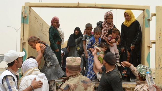 Iraqi soldiers help civilians who have fled Falluja during a dust storm on the outskirts of the city, Iraq, 18 June, 2016