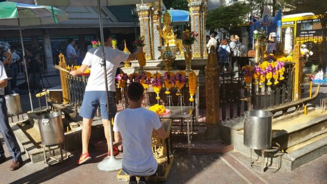 Men place flowers at the Erawan Shrine in Bangkok (19 Aug 2015)